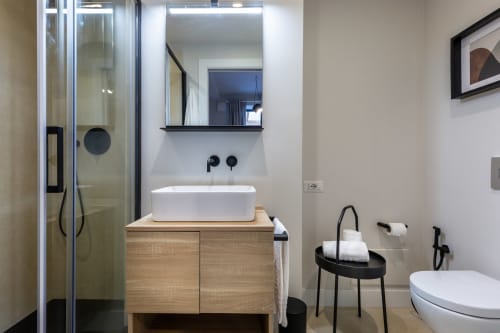 Bagno moderno di Casa Lounge Istria a Cagliari con lavabo in ceramica bianca, mobile in legno, doccia e arredamenti neri contemporanei