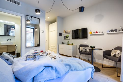 Camera moderna presso Casa Lounge Istria B&B a Cagliari con biancheria blu, TV a parete, lampade a sospensione e zona relax