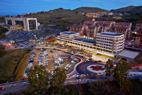Vista aerea di Sicilianinsta Rooms B&B a Catania con edifici moderni, parcheggi e colline circostanti al tramonto