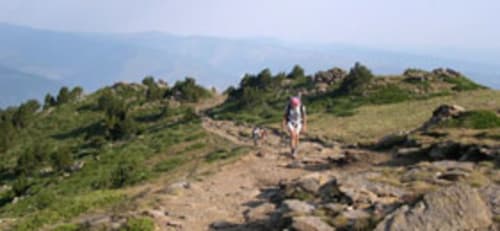 Randonneur sur le sentier rocheux de la montagne près de Vernet-les-Bains, vallées verdoyantes et pics en arrière-plan