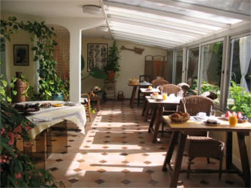 Salle de petit-déjeuner lumineuse aux Chambres D'hôtes Les2lions à Vernet-les-Bains, avec plantes, tables à manger et lumière naturelle