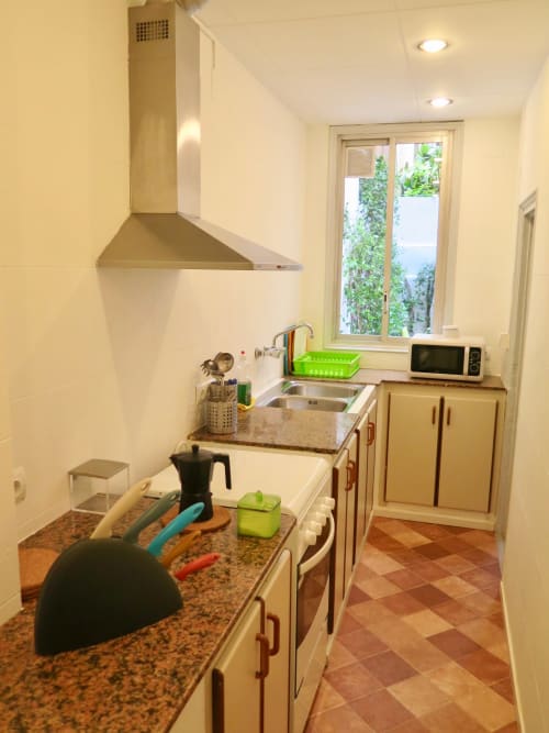 Modern kitchen at Mira Barna Barcelona apartment with stainless steel sink, white cabinetry, granite countertop, and garden