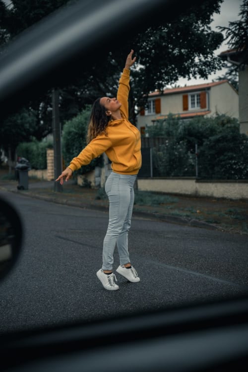 Femme en veste jaune sautant dans la rue près du Pavillon M à Grignan, France