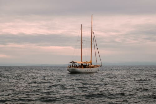 Voilier classique à deux mâts ancré dans des eaux calmes sous un ciel couvert
