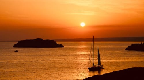 Golden sunset over Mediterranean waters with sailboat and islands near Grignan, France hospitality destination