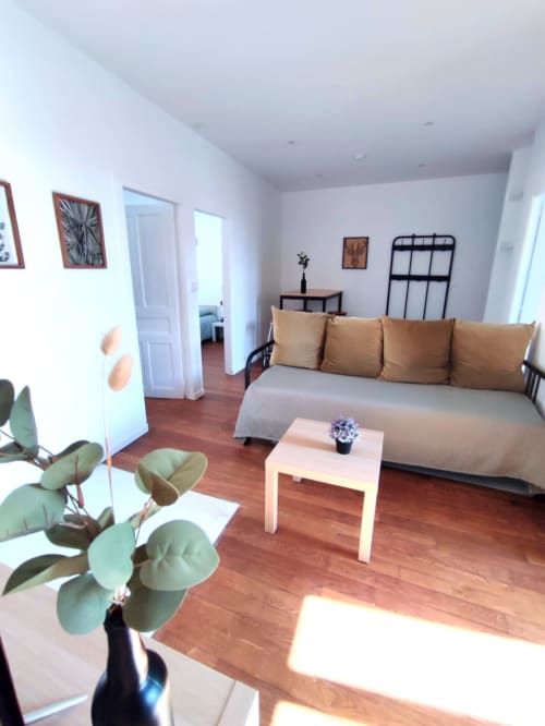 Studio lumineux à Lesdoucesnuits45 à Montargis avec canapé beige, table basse blanche, parquet et vue sur la ville