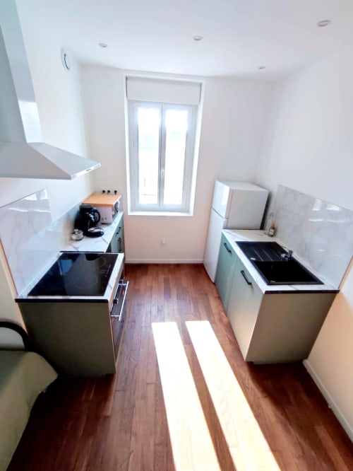 Cuisine moderne dans un appartement à Montargis avec deux foyers, réfrigérateur et lumière naturelle des portes-fenêtres