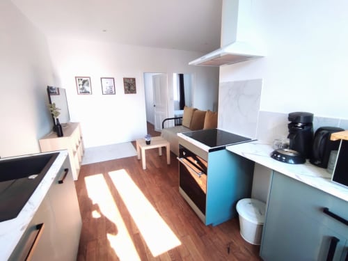 Cuisine et séjour modernes de l'appartement Lesdoucesnuits45 à Montargis avec parquet, cuisinière et coin salon