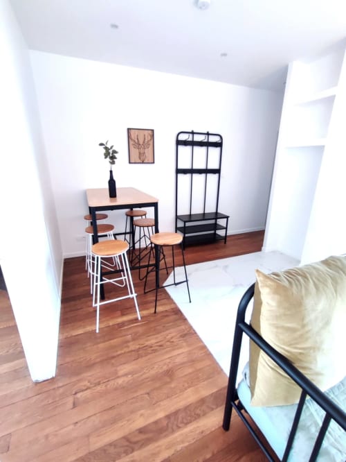 Séjour moderne et espace de dining à l'appartement Lesdoucesnuits45 à Montargis avec table en bois, tabourets de bar et étagères noires