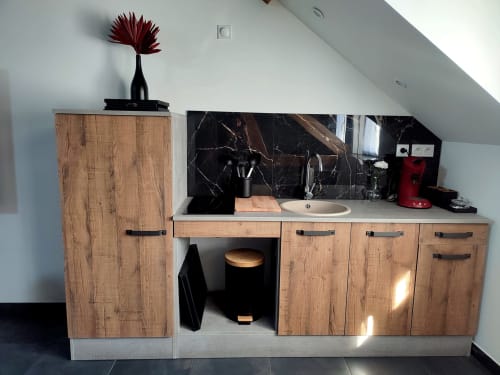 Kitchenette moderne aux armoires en bois, crédence en marbre noir et évier rond à l'appartement Lesdoucesnuits45 à Montargis