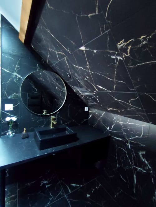 Salle de bain moderne en marbre noir avec miroir rond et lavabo à l'appartement Lesdoucesnuits45 à Montargis