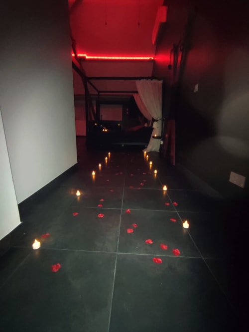 Couloir romantique de l'appartement Lesdoucesnuits45 à Montargis avec éclairage néon rouge, bougies et pétales de rose