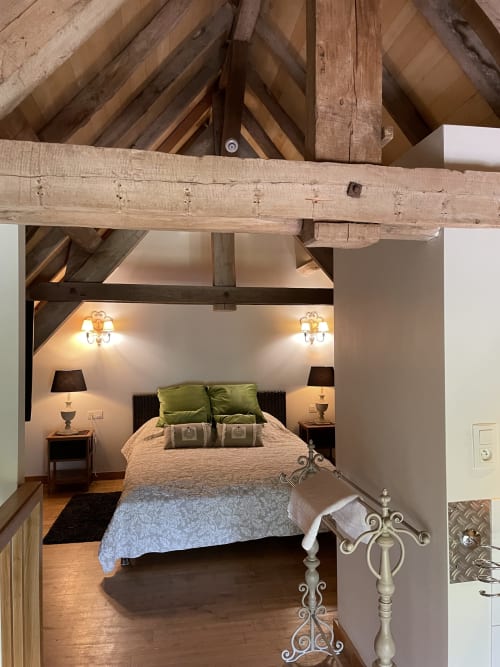 Chambre rustique aux Chambres d'hôtes Les Pratges à Figeac avec poutres apparentes, oreillers verts, lampes jumelées et parquet