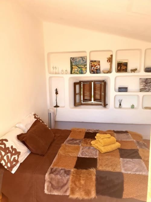 Chambre cosy de la villa Las Fincas De Annie avec courtepointe patchwork, étagères murales et volets bois surplombant Felanitx