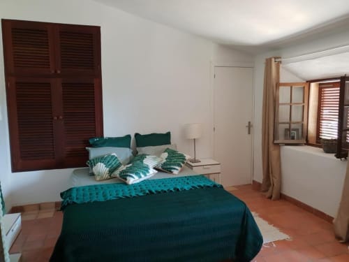 Chambre spacieuse de la villa Las Fincas De Annie à Felanitx avec literie bleu-vert, volets en bois et carrelage en terre cuite