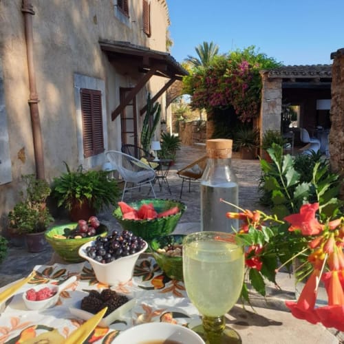 Repas en terrasse aux Fincas De Annie à Felanitx : fruits frais, rafraîchissements et architecture méditerranéenne rustique.