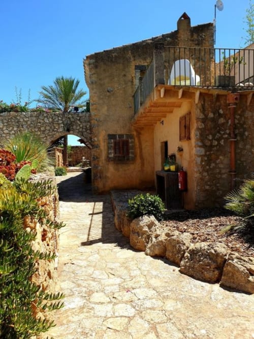 Cour de l'hôtel Las Fincas De Annie à Felanitx avec bâtiment ocre, murs de pierre et jardins méditerranéens sous un ciel bleu