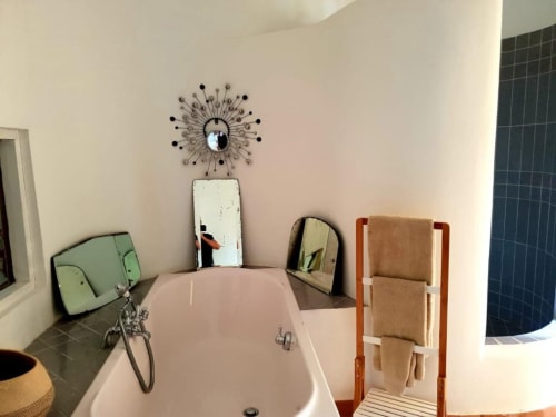 Salle de bains moderne aux Fincas De Annie à Felanitx avec baignoire blanche, miroir soleil décoratif et porte-serviettes en bois