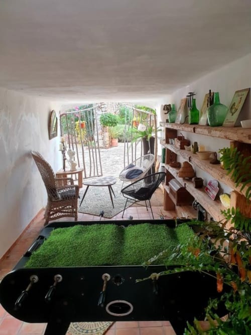 Terrasse cosy aux Fincas De Annie à Felanitx avec plantes vertes, étagères en bois, coin détente et vue sur le jardin