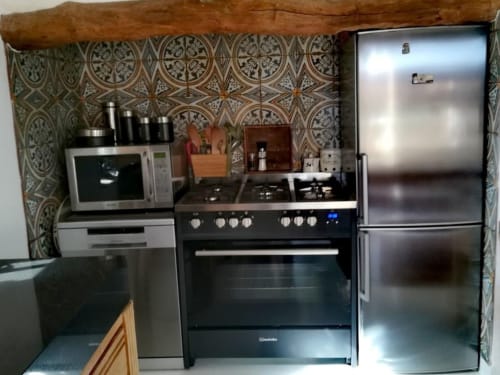 Cuisine moderne aux Fincas De Annie à Felanitx avec électroménagers en acier inoxydable, dosseret à motifs et cuisinière à gaz.