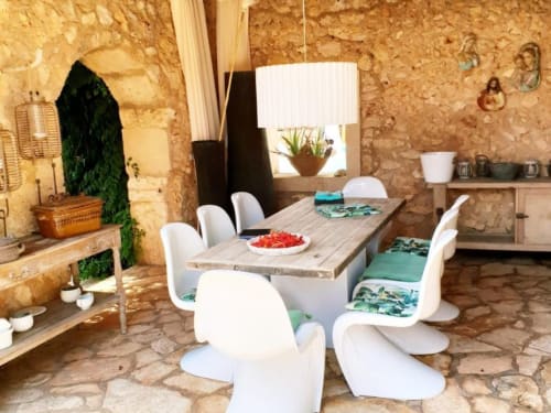 Salle à manger rustique en pierre aux Las Fincas De Annie avec chaises modernes blanches, table en bois et décoration méditerranéenne à Felanitx