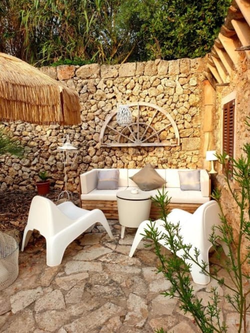 Patio en pierre rustique aux Fincas De Annie à Felanitx, mobilier blanc et décoration de roue de chariot
