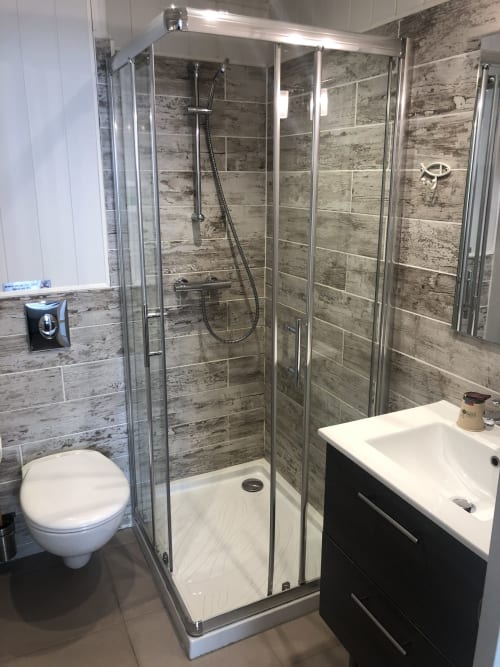 Modern bathroom at Hôtel Maison Richet with walk-in shower, white sink, toilet, and wood-look tiles