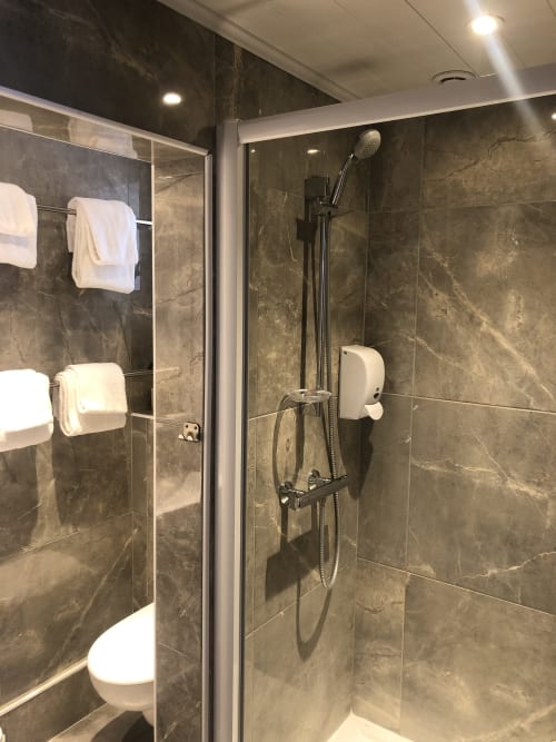 Modern bathroom with dark marble tiles, walk-in shower, toilet, and white towels at Hôtel Maison Richet, Les Sables-d'Olonne