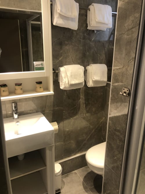 Modern bathroom at Hôtel Maison Richet with dark tile shower, white sink, toilet, and white towels in Les Sables-d'Olonne