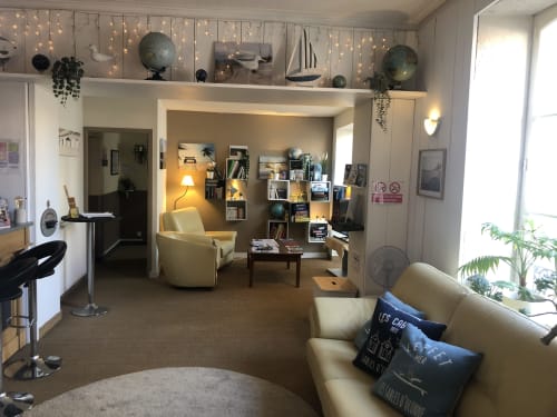Cozy lounge at Hôtel Maison Richet B&B in Les Sables-d'Olonne with cream armchairs, shelving, warm lighting and plants.
