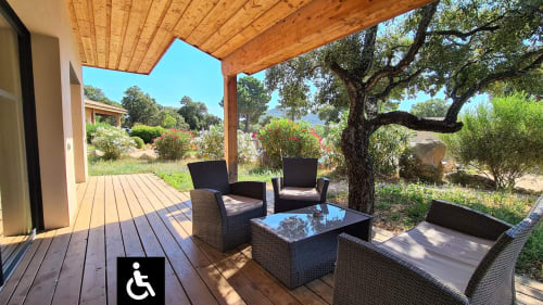 Wheelchair accessible villa patio with wicker seating and glass table overlooking Corsican gardens at Villas Lantana, Lecci