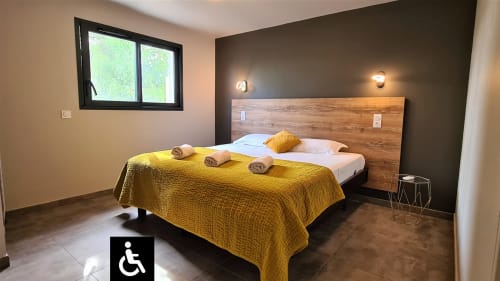 Accessible bedroom at Villas Lantana B&B in Lecci with wooden bed frame, yellow bedding, and modern amenities.