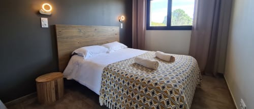 Modern bedroom at Villas Lantana in Lecci with wooden bed frame, white linens, patterned throw, ring lights, and windows