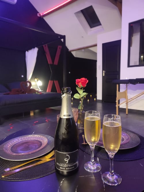 Ambiance romantique avec champagne, rose rouge, verres et table élégamment dressée à l'appartement Lesdoucesnuits45 à Montargis