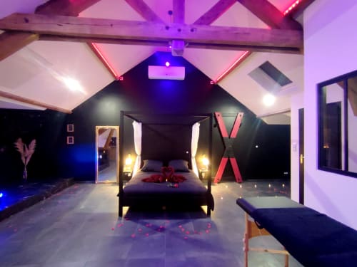 Chambre luxueuse aux néons rose, lit à baldaquin et pétales de roses aux Douces Nuits 45 à Montargis