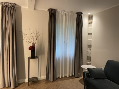 Elegant living room at Covo del Pirata Venice with layered curtains, black sofa, decorative vase, and herringbone flooring