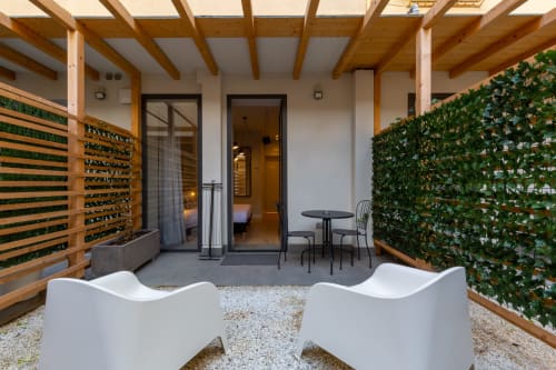 Cortile moderno con pareti verdi, sedute bianche e pergolato in legno a Casa Lounge Istria a Cagliari