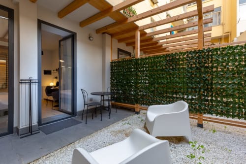 Terrazza giardino Casa Lounge Istria con lettini bianchi, parete verde, pergolato in legno e accesso interno a Cagliari