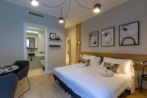 Camera moderna a Casa Lounge Istria, Cagliari con letto bianco, testata in legno, bagno in camera e arredamento contemporaneo