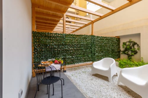 CASA LOUNGE ISTRIA sala giardino con parete di edera artificiale, pergolato in legno, sedie bianche e tavolo da pranzo a Cagliari