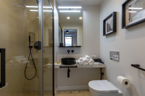 Bagno moderno a Casa Lounge Istria a Cagliari con finiture nere, lavabo a bacinella, doccia a filo pavimento e asciugamani arrotolati