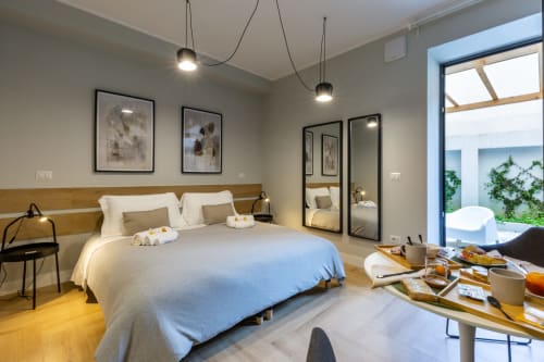 Camera moderna a Casa Lounge Istria a Cagliari con biancheria blu, testiera in legno, luci sospese e porte in vetro