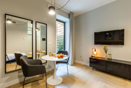 Camera moderna di Casa Lounge Istria a Cagliari con tavolo rotondo, sedie scure, TV e camera con specchio
