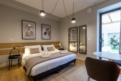 Camera moderna a Casa Lounge Istria di Cagliari con testata in legno, armadio specchiato, lampade a sospensione e accesso al patio