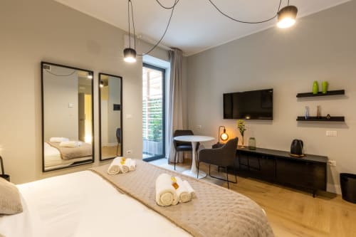 Camera moderna a Casa Lounge Istria a Cagliari con letto, specchio, TV, scrivania e accesso al balcone