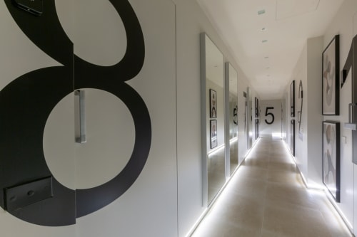Corridoio moderno dell'hotel Casa Lounge Istria a Cagliari con pavimento illuminato, porte numerate e arte geometrica alle pareti