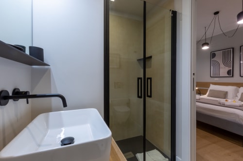 Bagno moderno con doccia in vetro e lavabo bianco a Casa Lounge Istria a Cagliari, vista sulla camera da letto