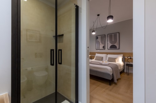 Camera da letto moderna con doccia in camera a CASA LOUNGE ISTRIA, Cagliari. Arredamento minimalista con arte contemporanea e lampada a sospensione