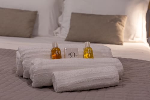 Asciugamani bianchi arrotolati con articoli da toeletta sul letto di Casa Lounge Istria, Cagliari