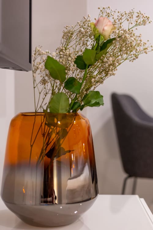 Garofano rosa con fiore di spirea in vaso di vetro ambrato nella camera dell'hotel Casa Lounge Istria, Cagliari